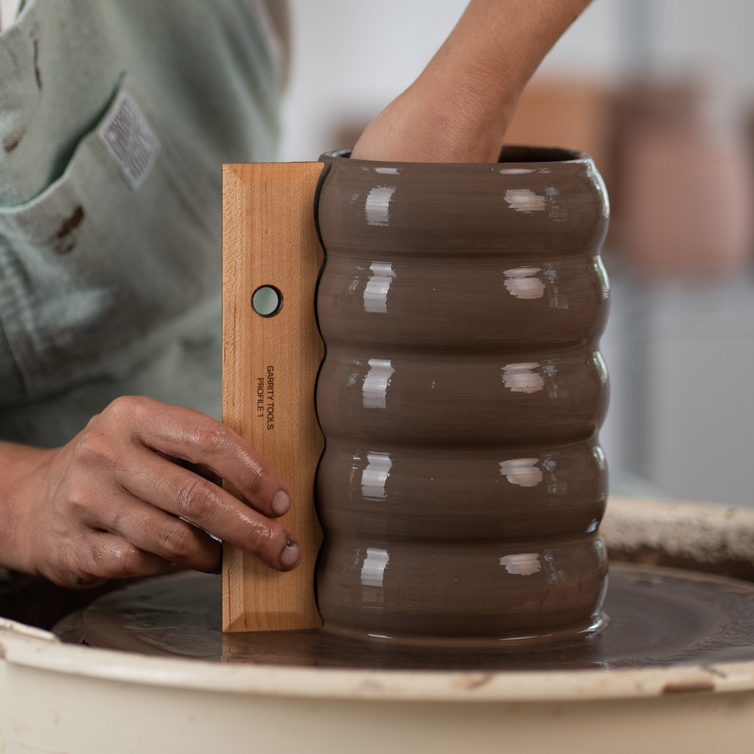 ceramicist uses Garrity Tools Profile 1 wood pottery rib to create a bubble pattern on clay vessel