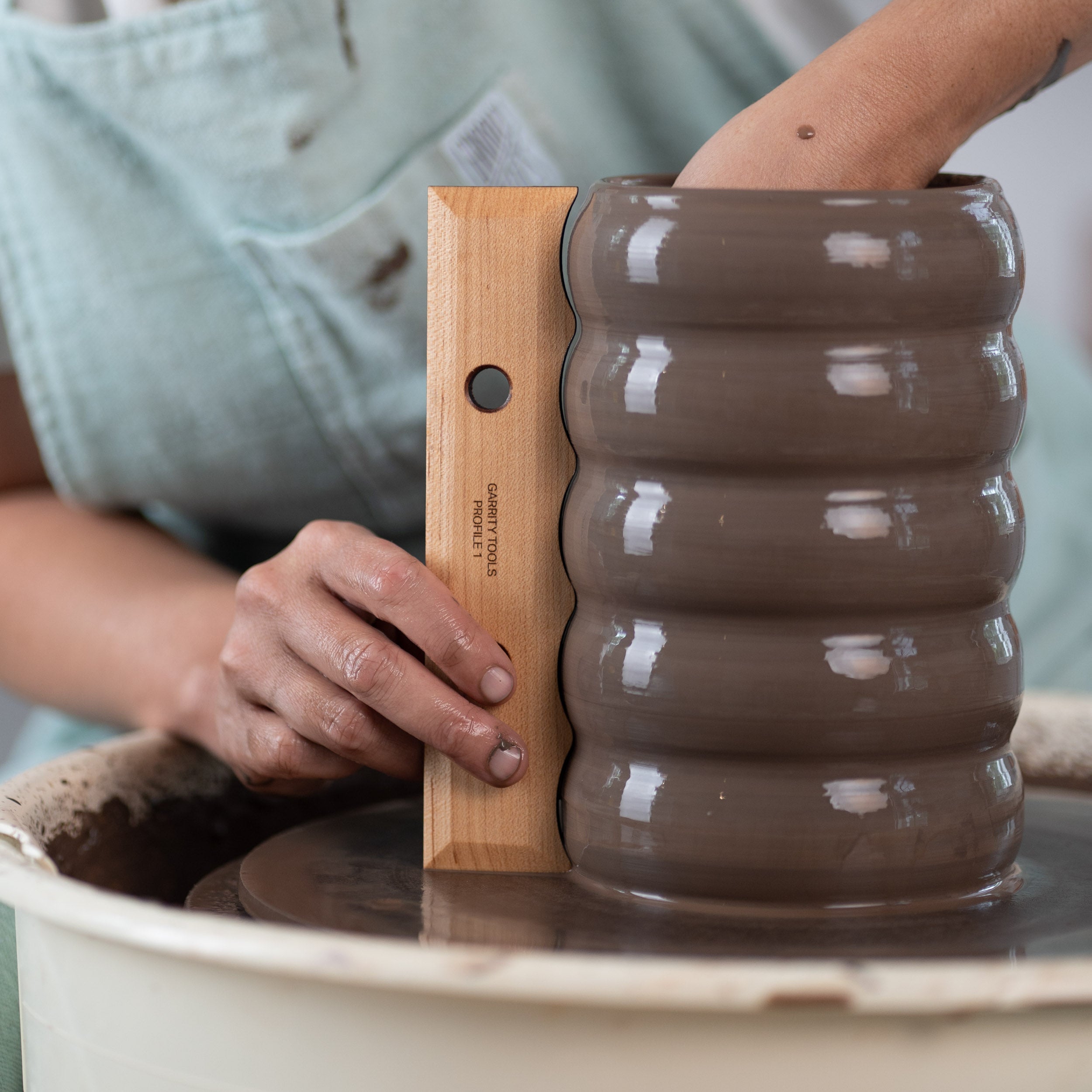 ceramicist uses Garrity Tools Profile 1 wood pottery rib to create a bubble pattern on clay vessel