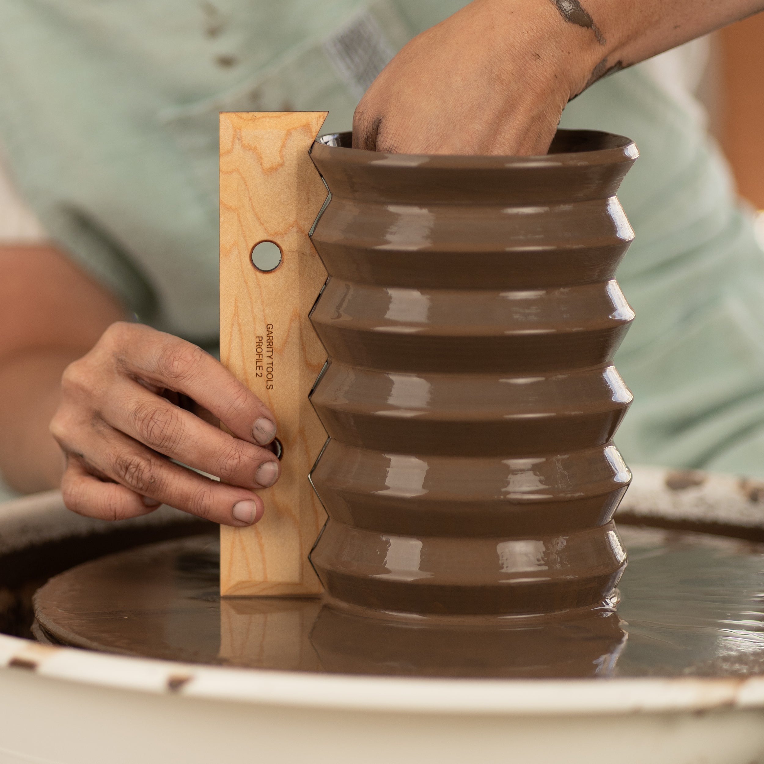 ceramicist uses Garrity Tools Profile 2 wood pottery rib to create a zig-zag pattern in clay vessel