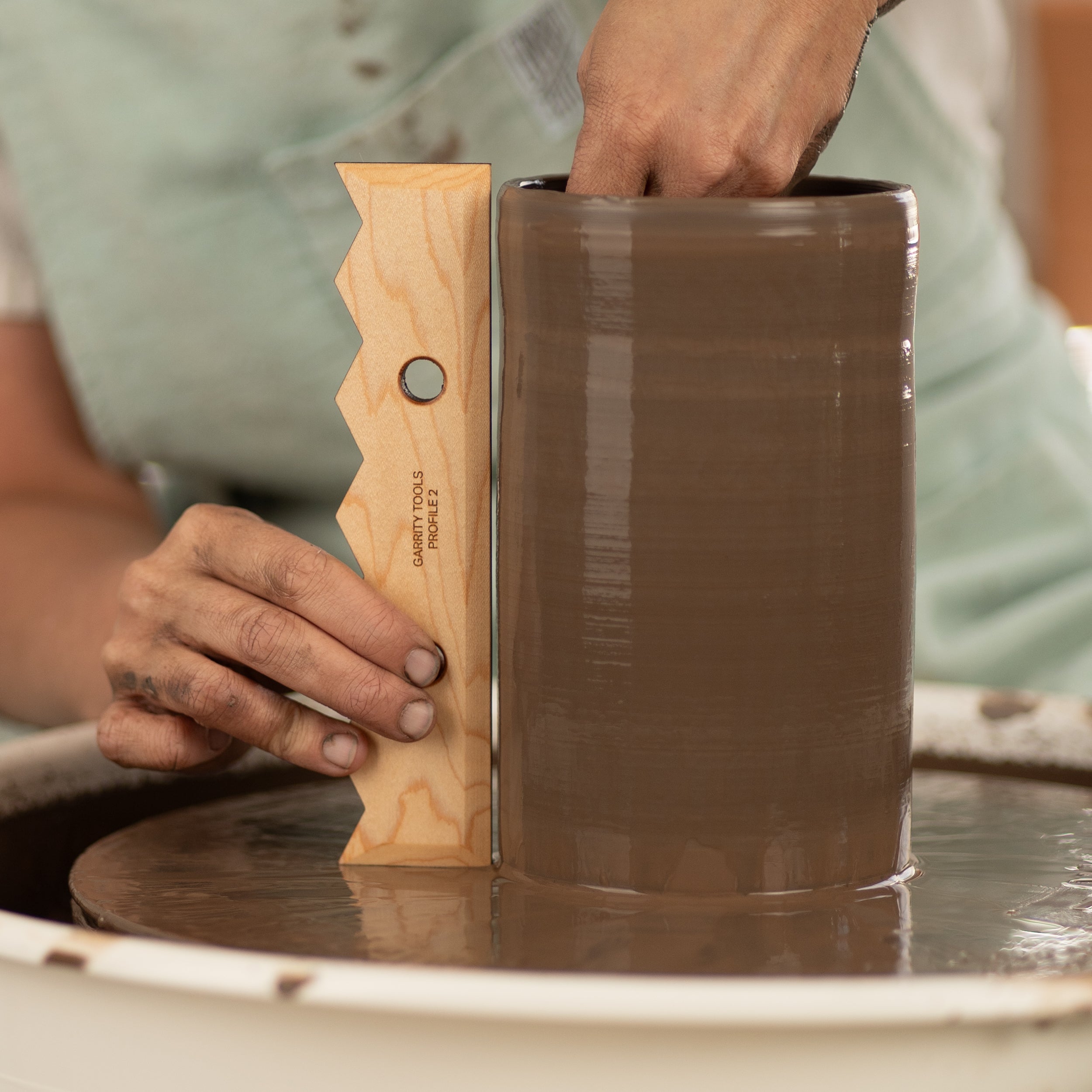 ceramicist uses Garrity Tools Profile 2 wood pottery rib on clay vessel