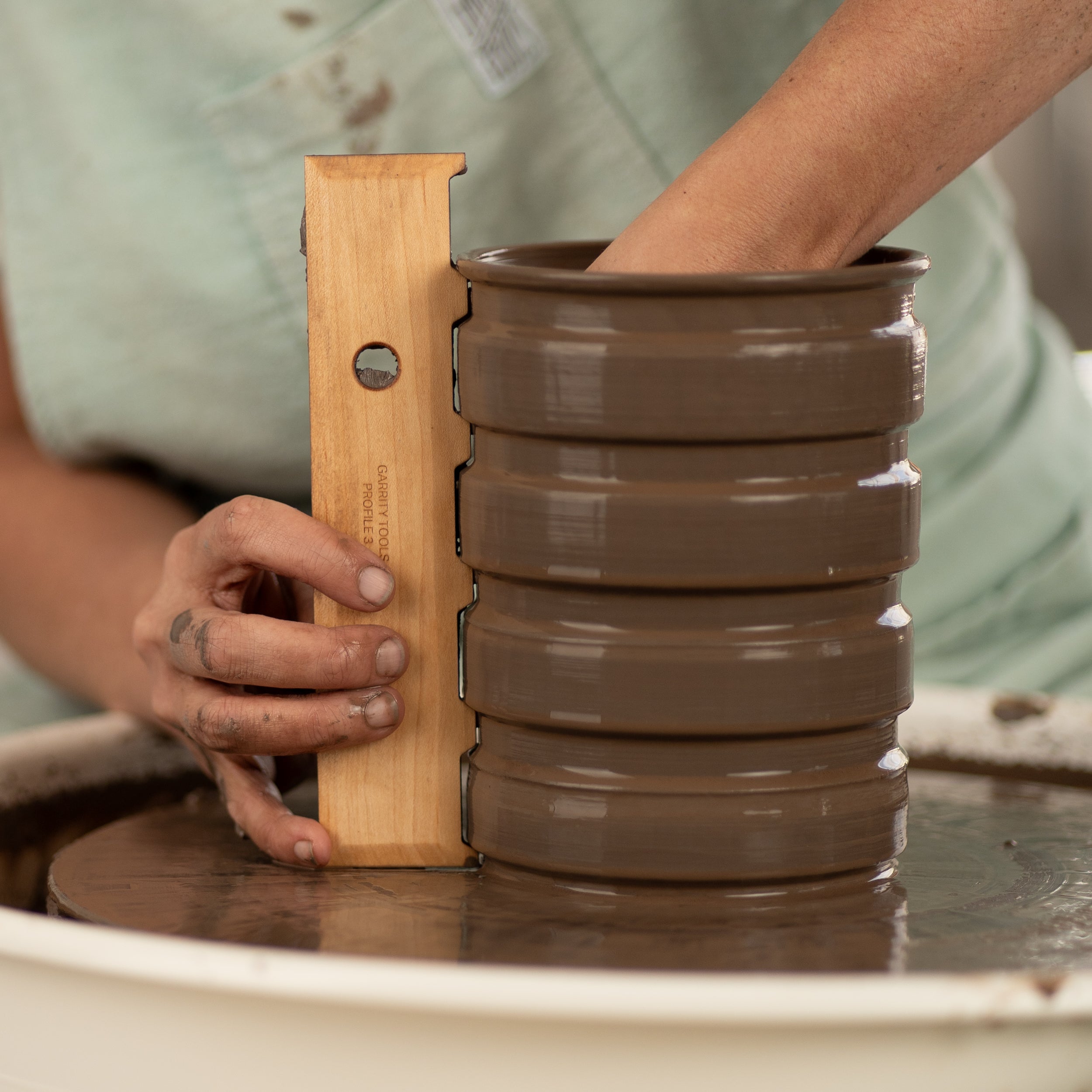 ceramicist uses Garrity Tools Profile 3 wood pottery rib on clay vessel