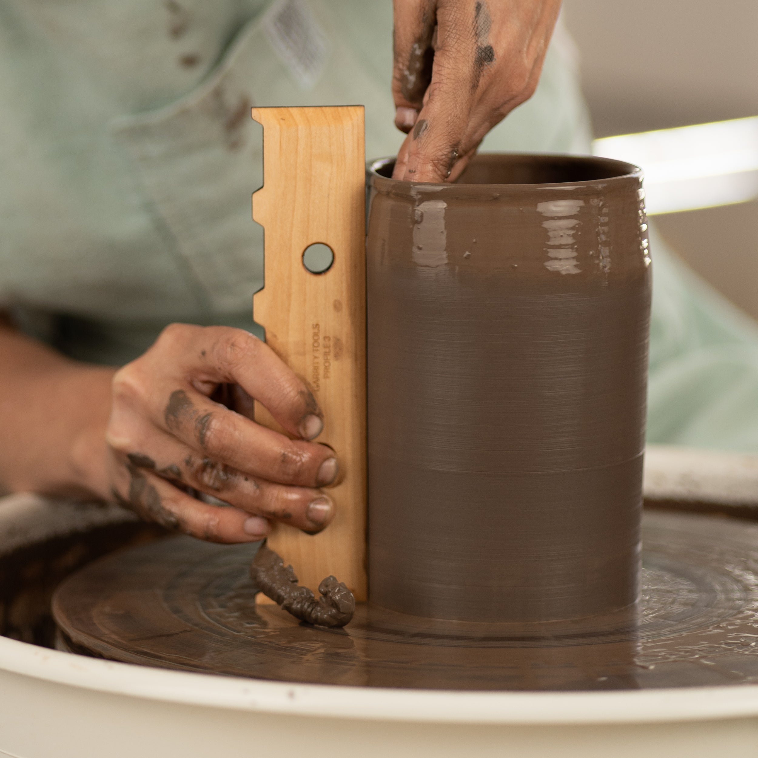 ceramicist uses Garrity Tools Profile 3 wood pottery rib on clay vessel