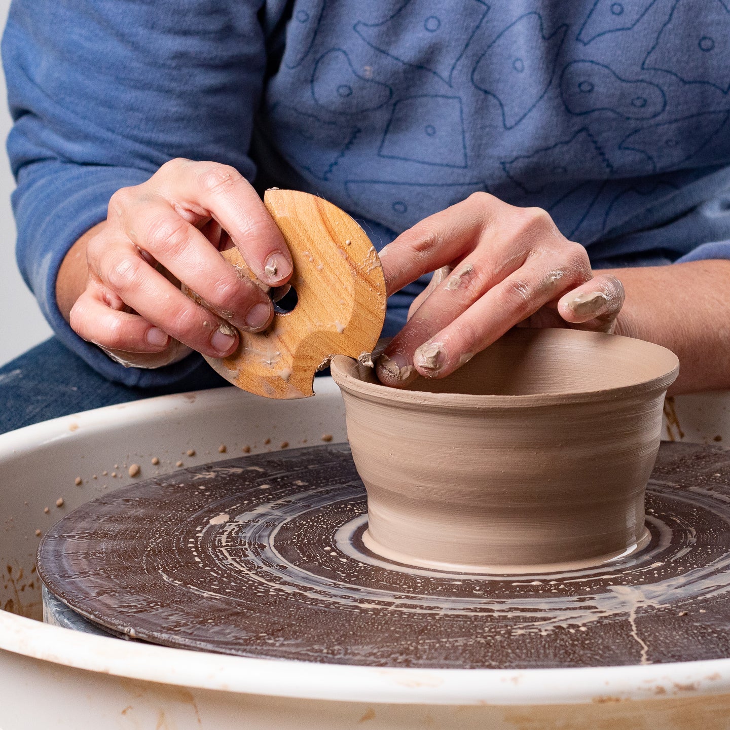 ceramicist using Garrity Tools A4 wooden pottery rib on clay pot