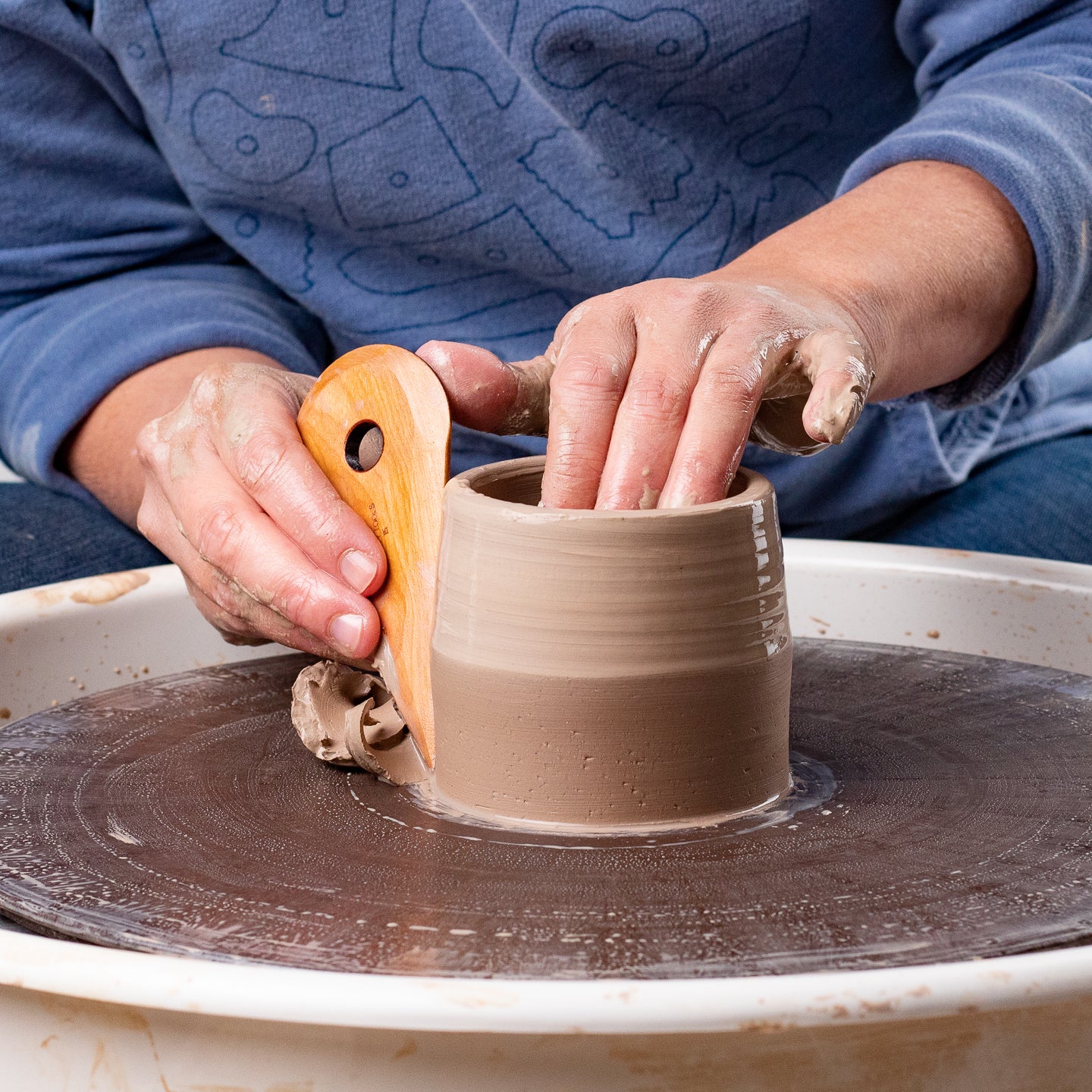 ceramicist uses Garrity Tools I5 wooden pottery tool on clay cylinder