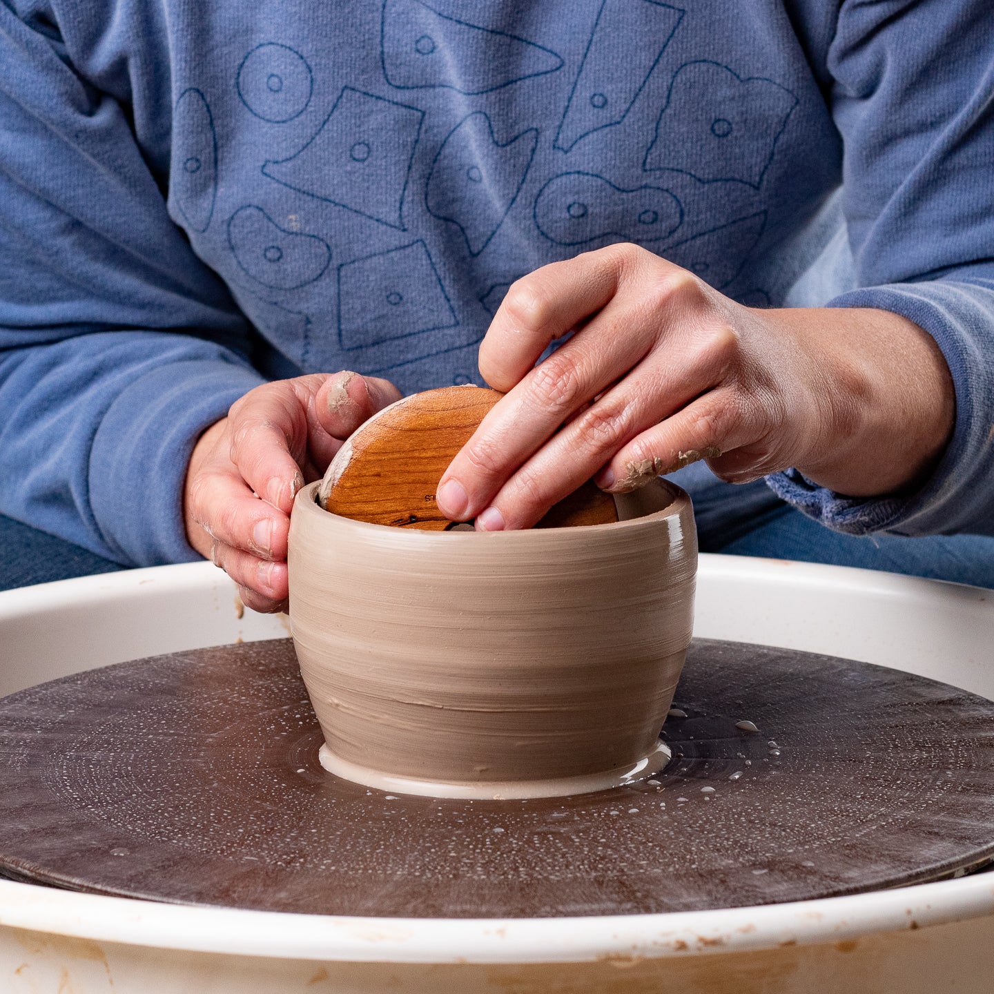 ceramicist uses Garrity Tools C4 wooden pottery rib on clay pot