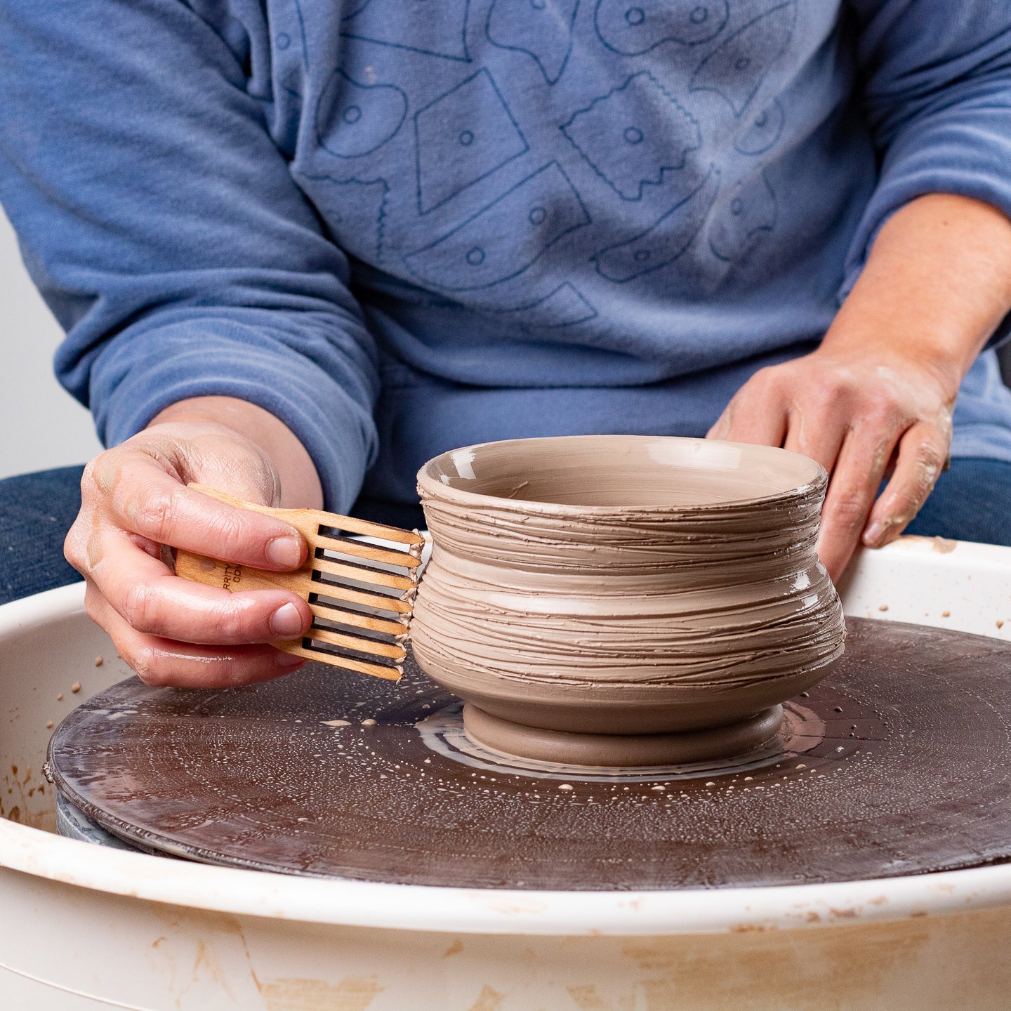 ceramicist uses Garrity Tools Comb wooden pottery rib to create texture on clay