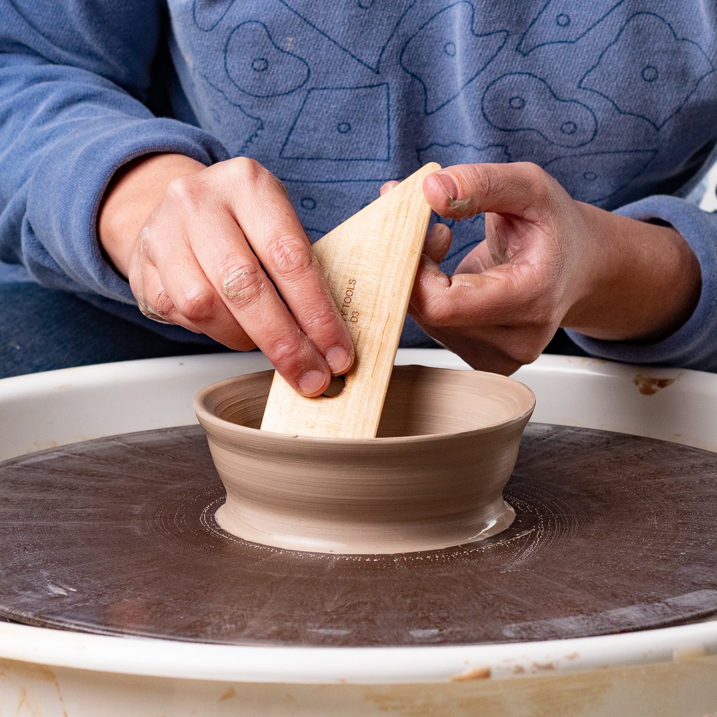 ceramicist uses Garrity Tools D3 wooden pottery tool on clay bowl