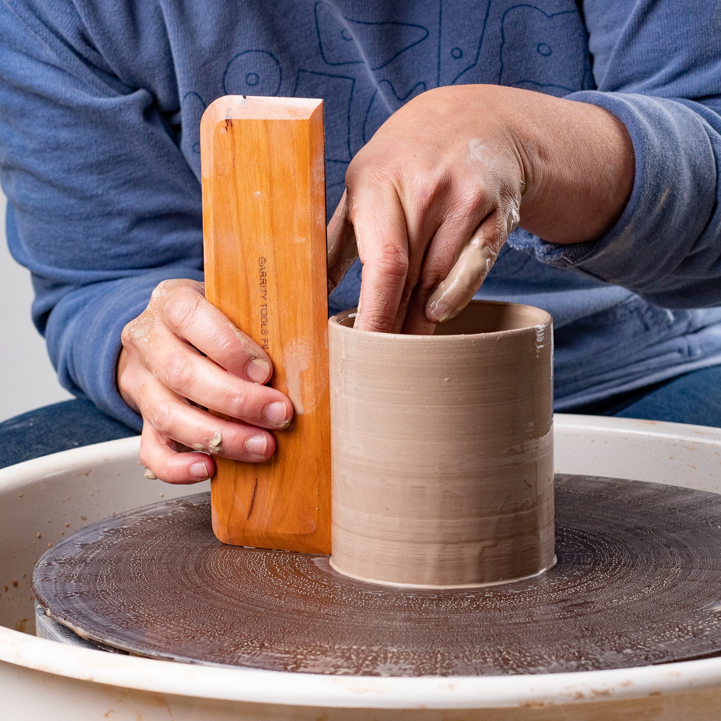 ceramicist uses Garrity Tools Fish Fillet wooden pottery tool on clay cylinder