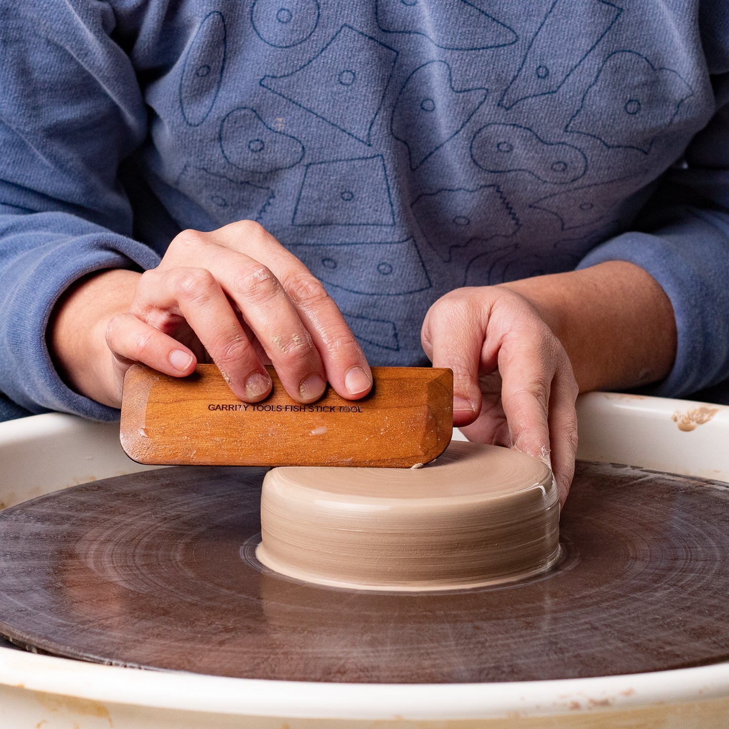 ceramicist uses Garrity Tools Fish Stick wooden pottery tool to compress clay