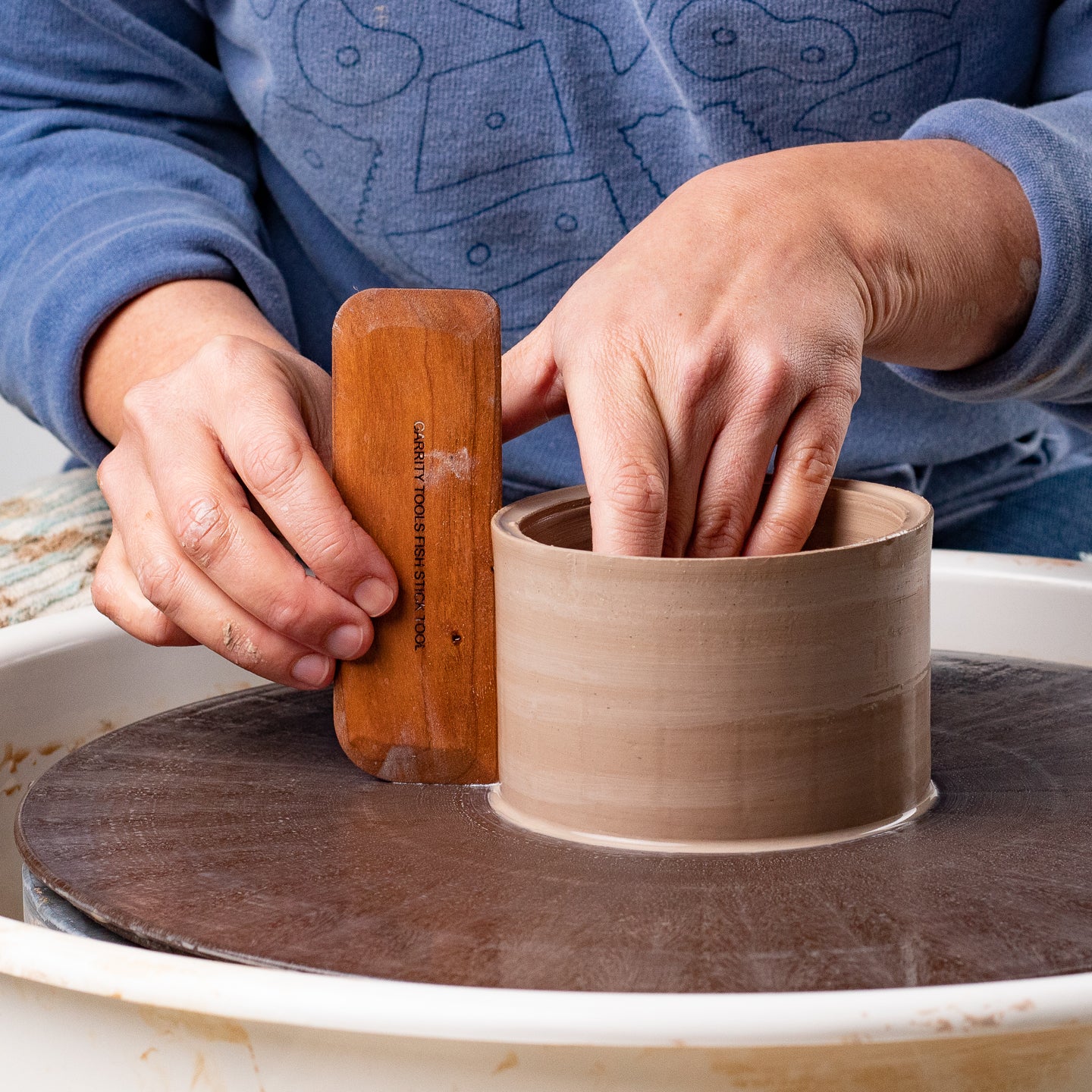 ceramicist uses Garrity Tools Fish Stick wooden pottery tool on clay cylinder