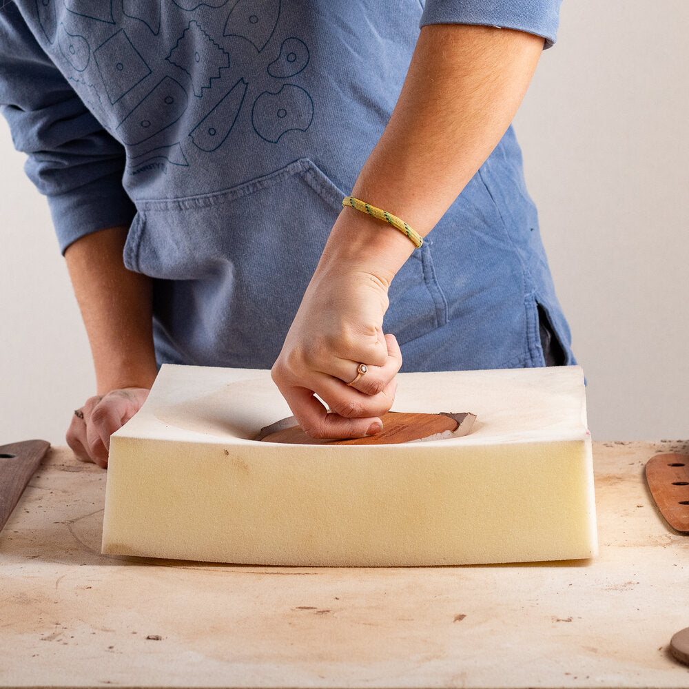 ceramicist pushing wooden mushroom anvil into a piece of foam