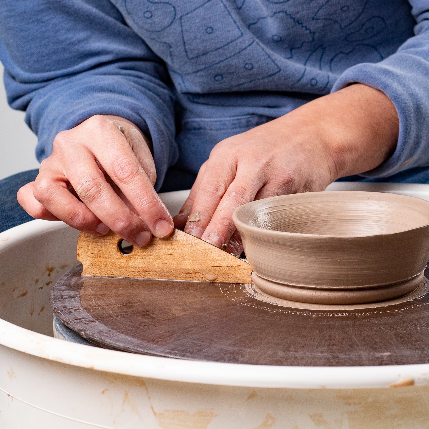 ceramicist uses Garrity Tools Foot 2 wooden pottery tool on clay bowl