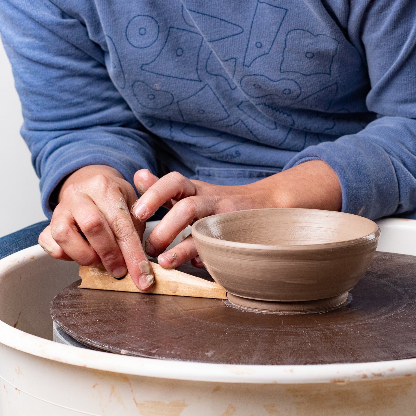 ceramicist uses Garrity Tools Foot 4 wooden pottery tool on clay bowl