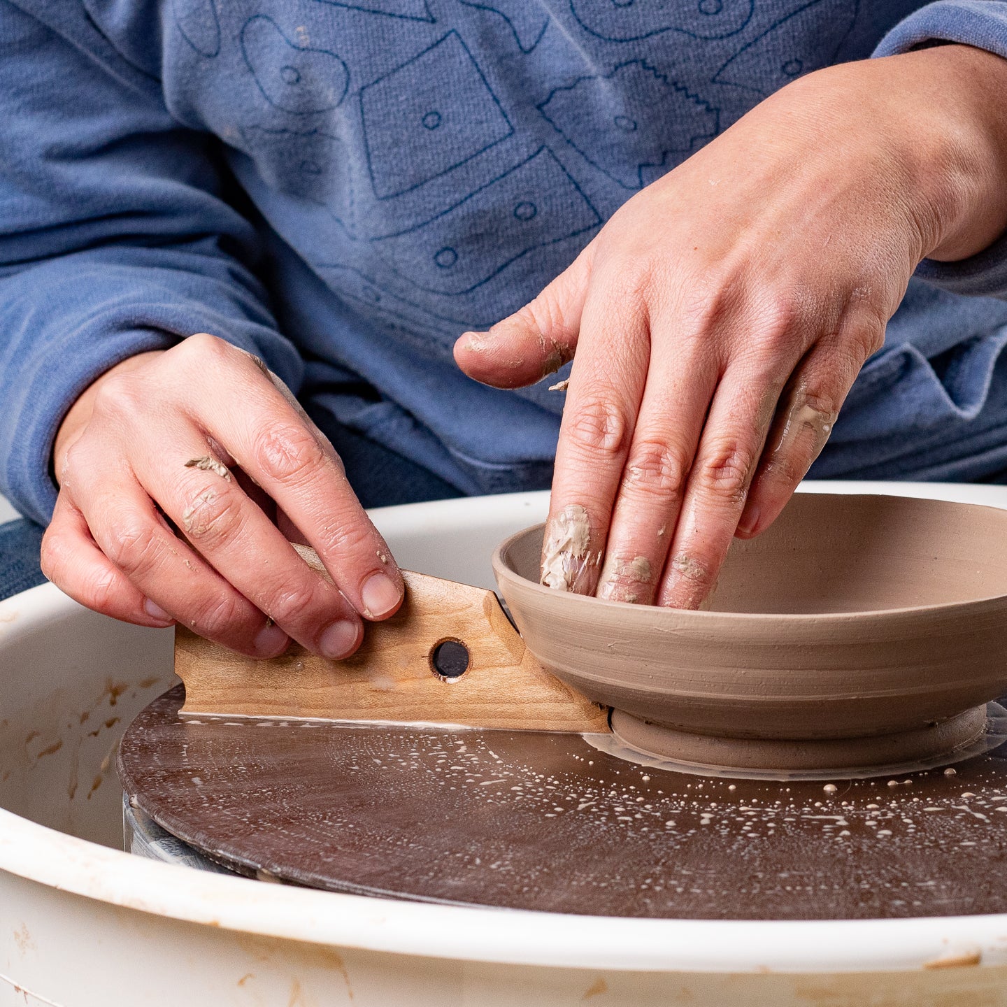 ceramicist uses Garrity Tools Foot 8 wooden pottery tool on clay bowl