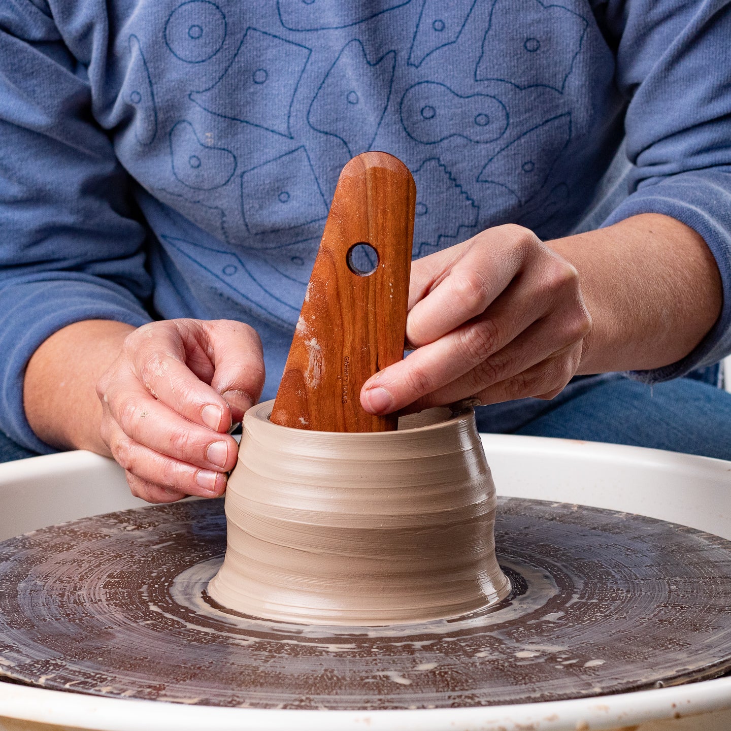 ceramicist uses Garrity Tools I1 wooden pottery tool on clay vessel