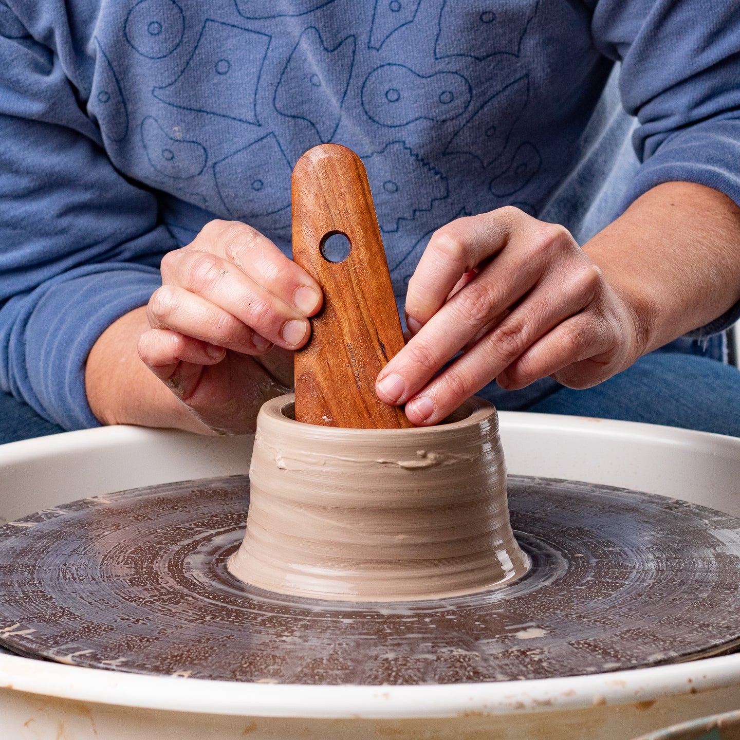 ceramicist uses Garrity Tools I1 wooden pottery tool on clay vessel