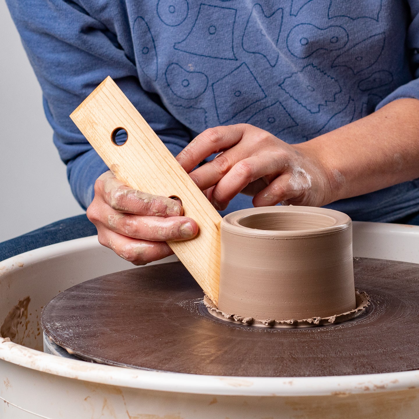 ceramicist uses Garrity Tools N1 wooden pottery tool on clay cylinder