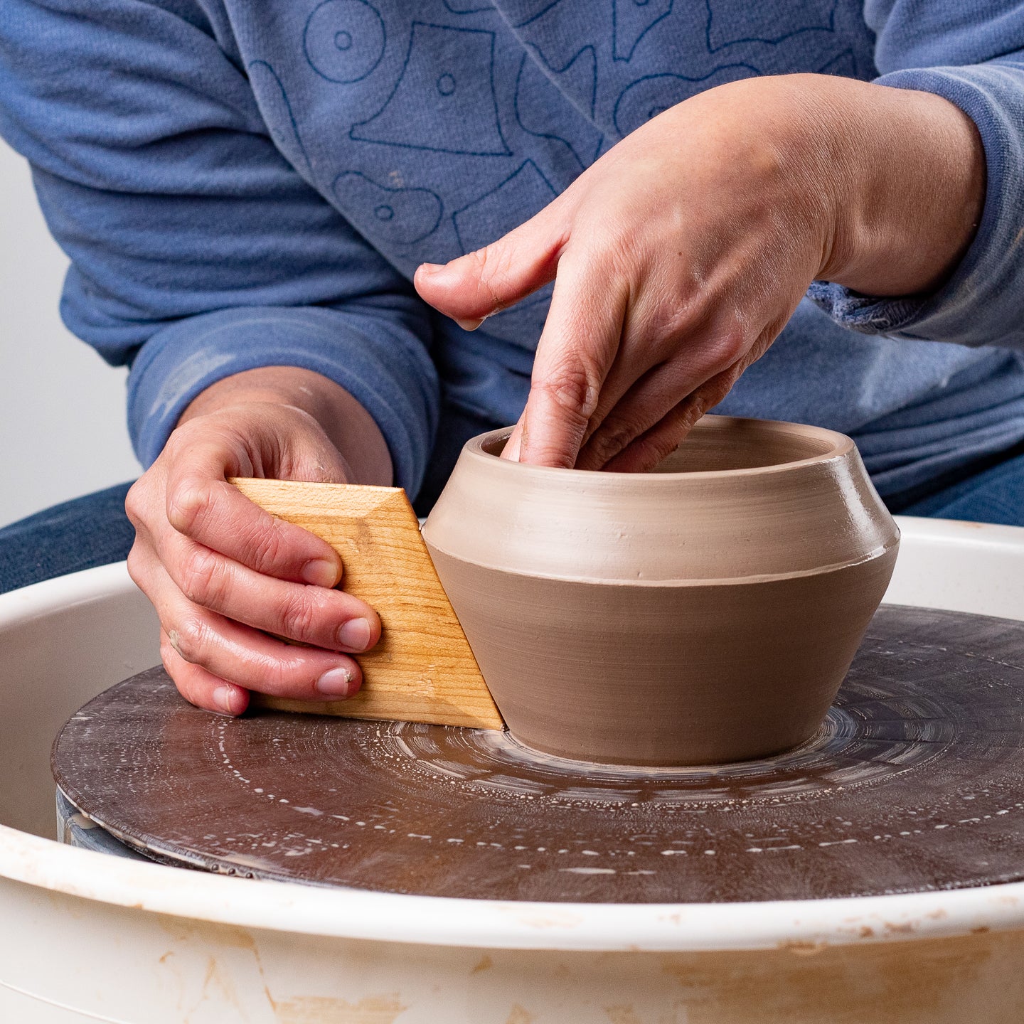 ceramicist uses Garrity Tools N3 wooden pottery tool on clay pot