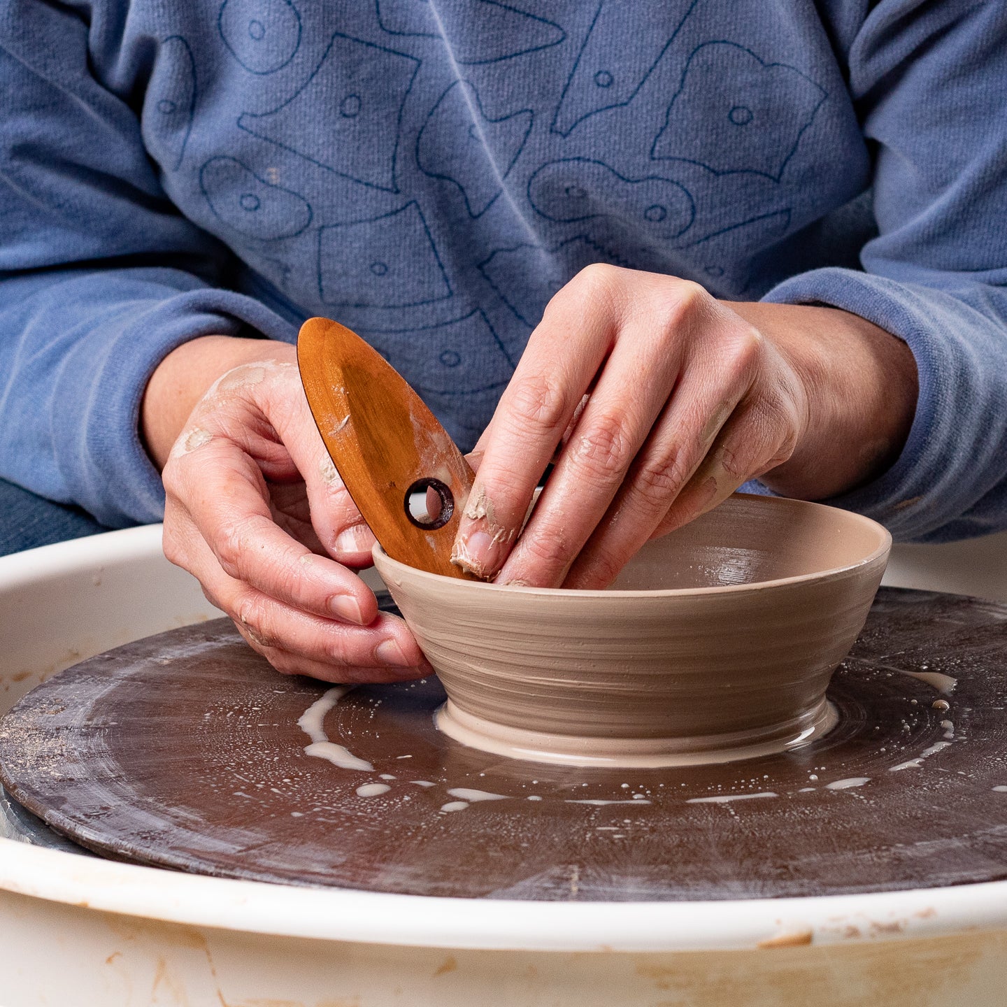 ceramicist uses Garrity Tools O6 wooden pottery tool on clay bowl