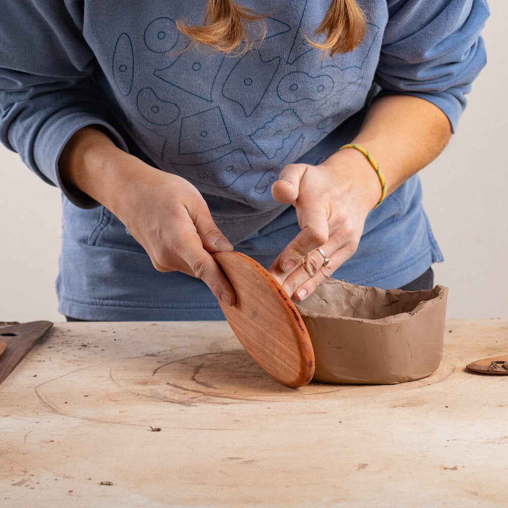 ceramicist uses Garrity Tools wooden paddle to shape clay