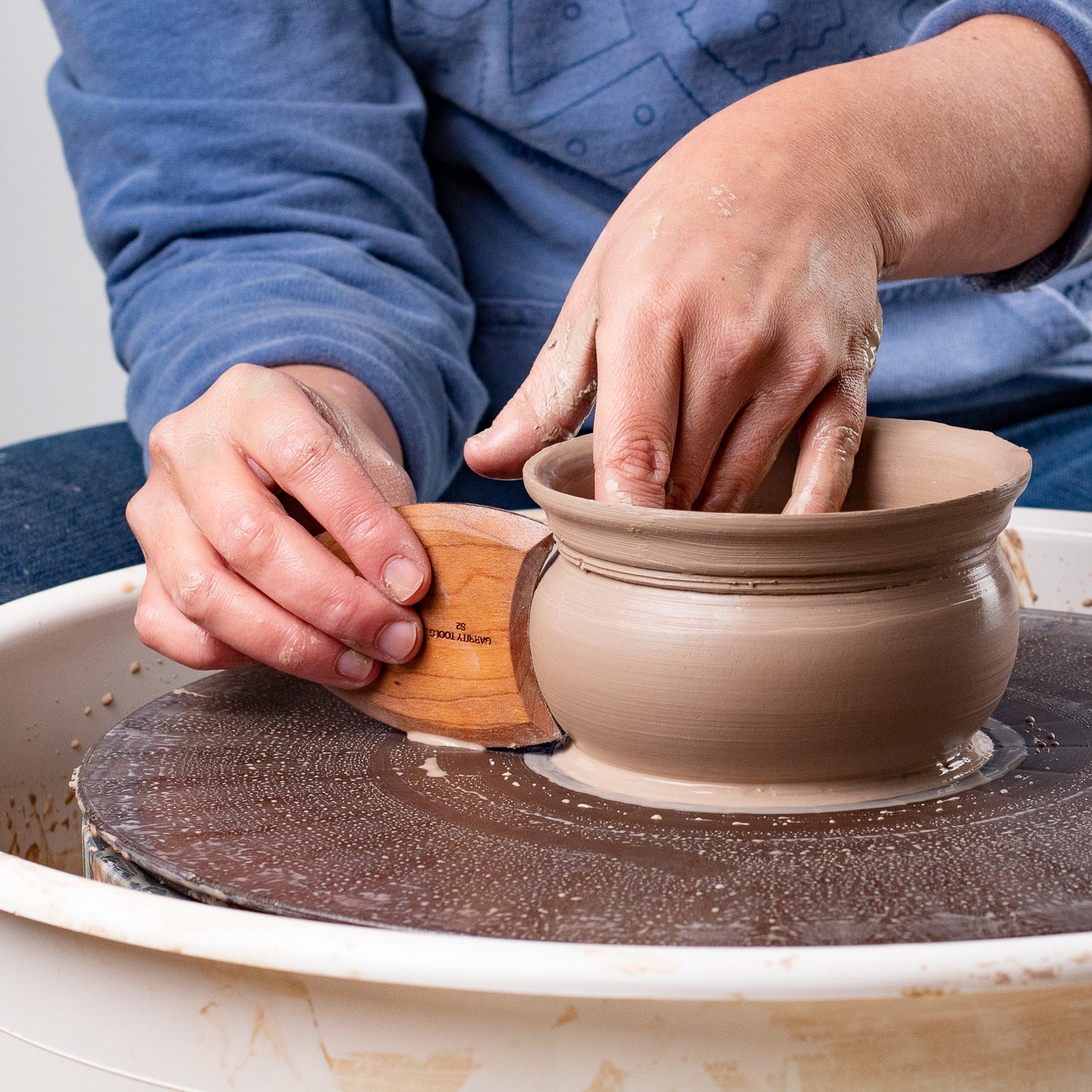 ceramicist uses Garrity Tools S2 wooden pottery tool on clay pot