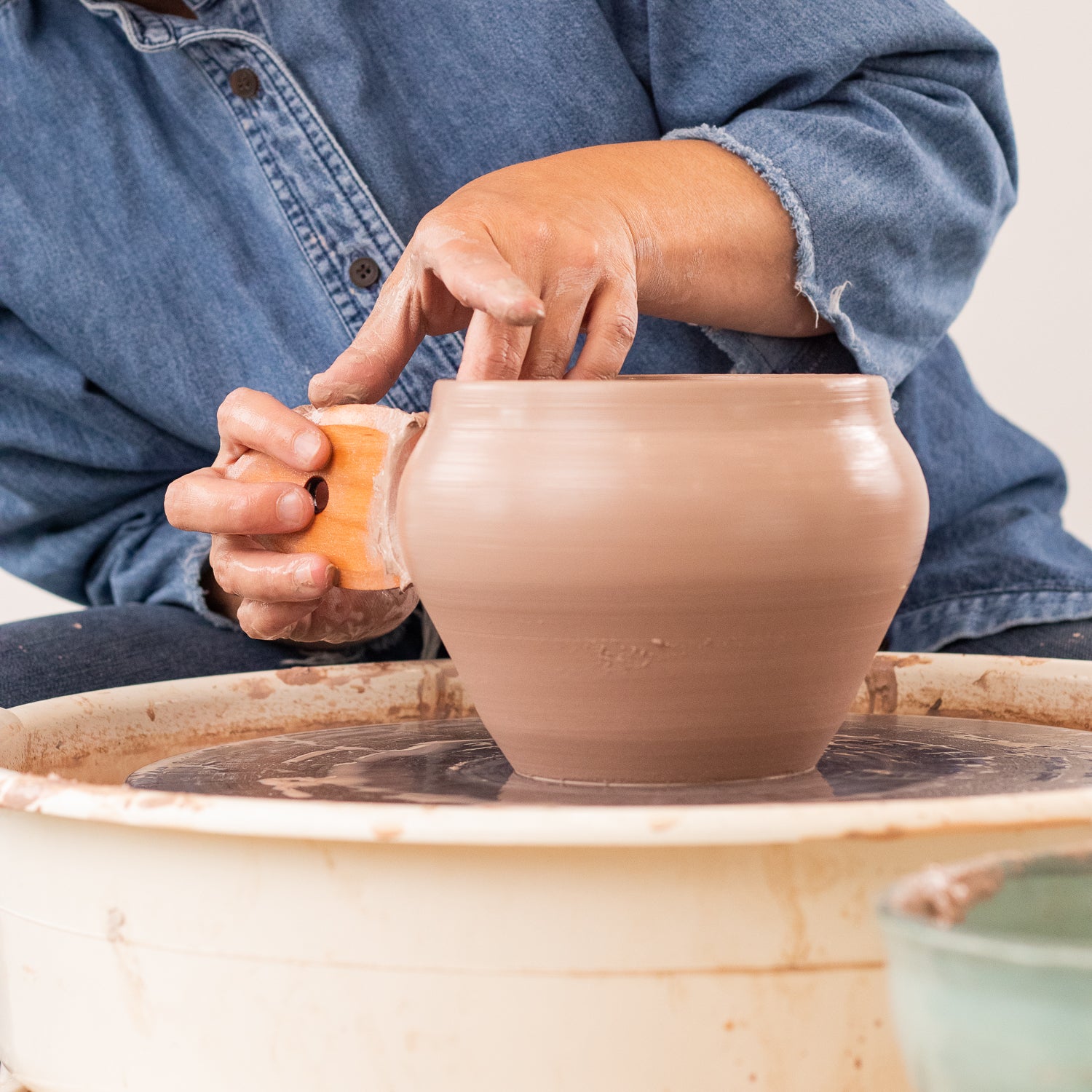 ceramicist uses Garrity Tools S2 wooden pottery tool on clay pot