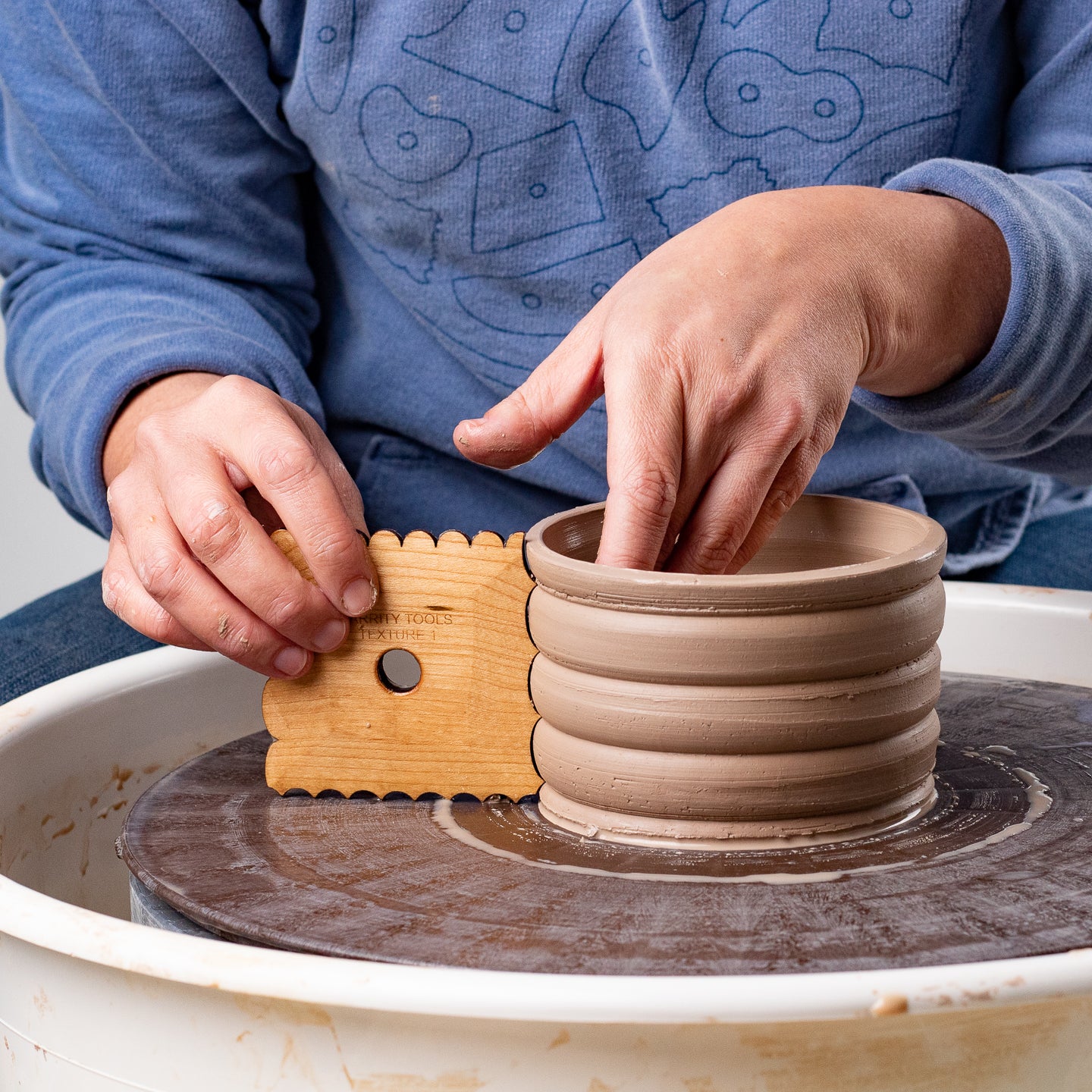 ceramicist uses Garrity Tools Texture 1 wooden pottery tool on pottery wheel