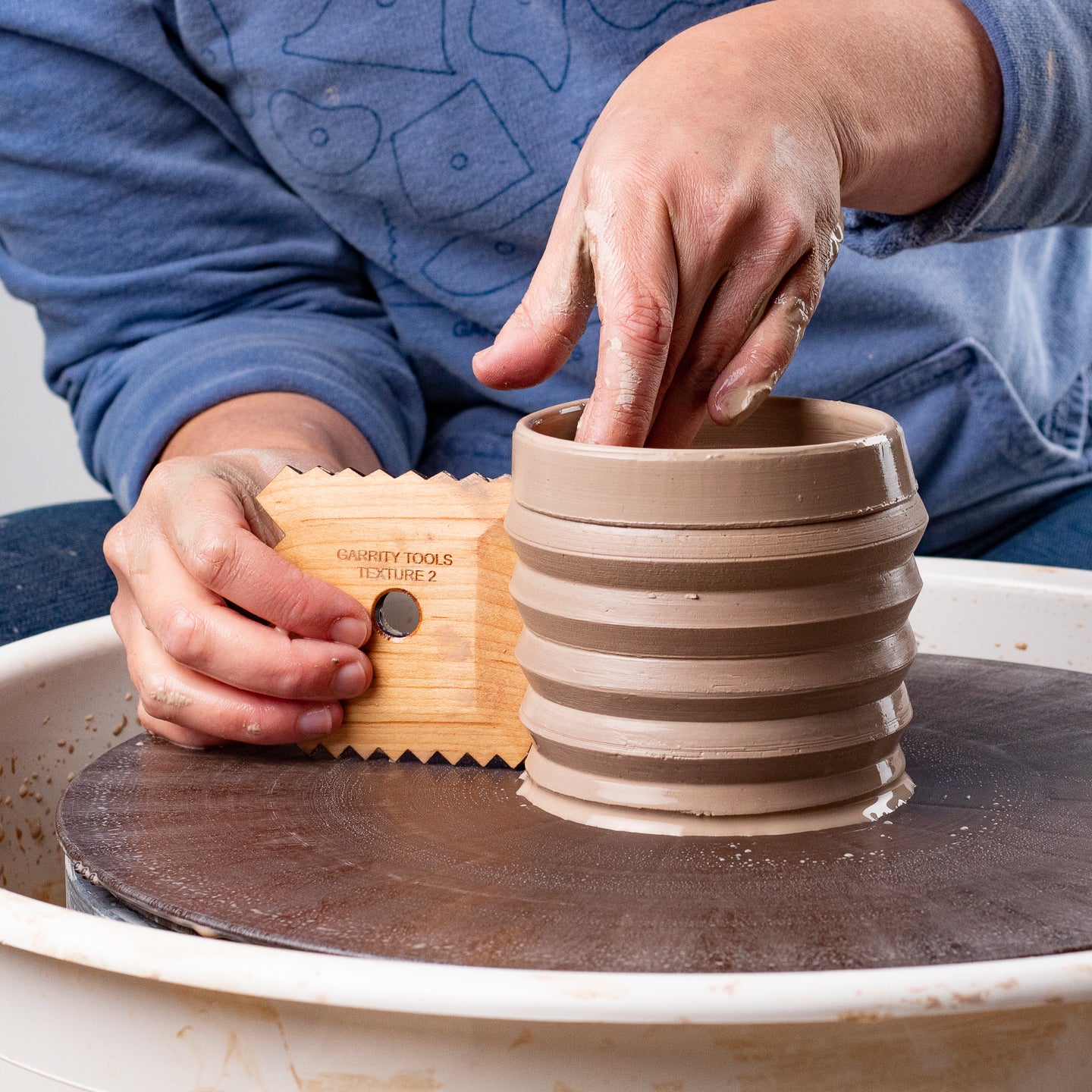 ceramicist uses Garrity Tools Texture 2 wooden pottery tool on pottery wheel