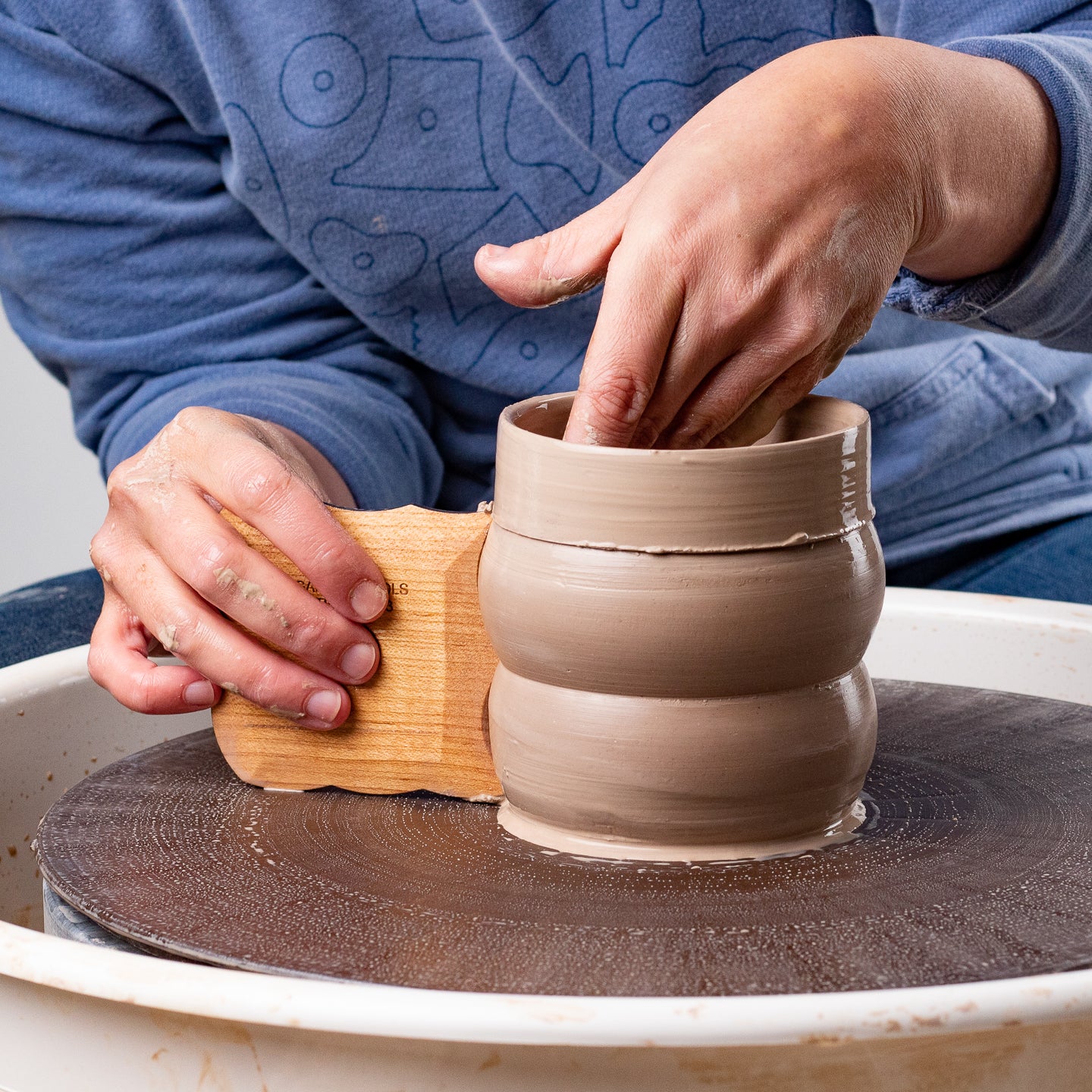 ceramicist uses Garrity Tools Texture 3 wooden pottery tool on pottery wheel