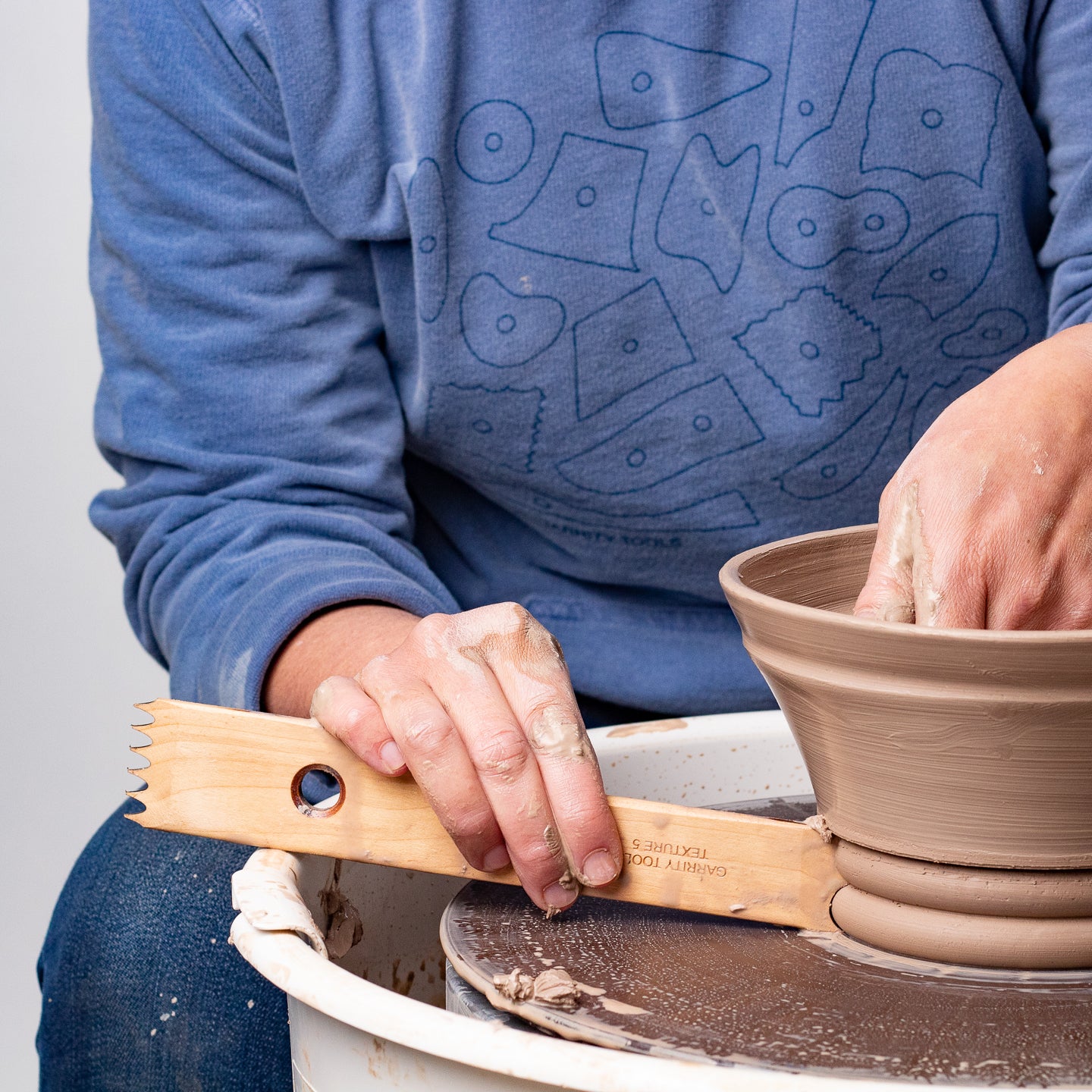 ceramicist uses Garrity Tools Texture 5 wooden pottery tool on clay bowl