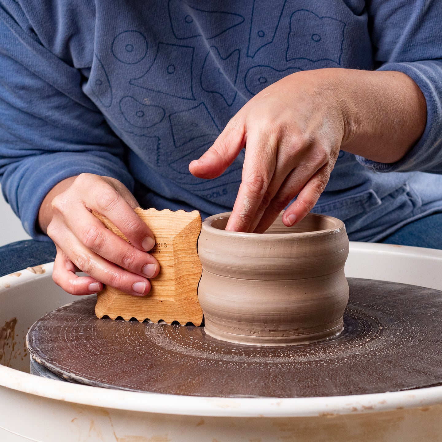 ceramicist uses Garrity Tools Texture 7 wooden pottery tool on pottery wheel