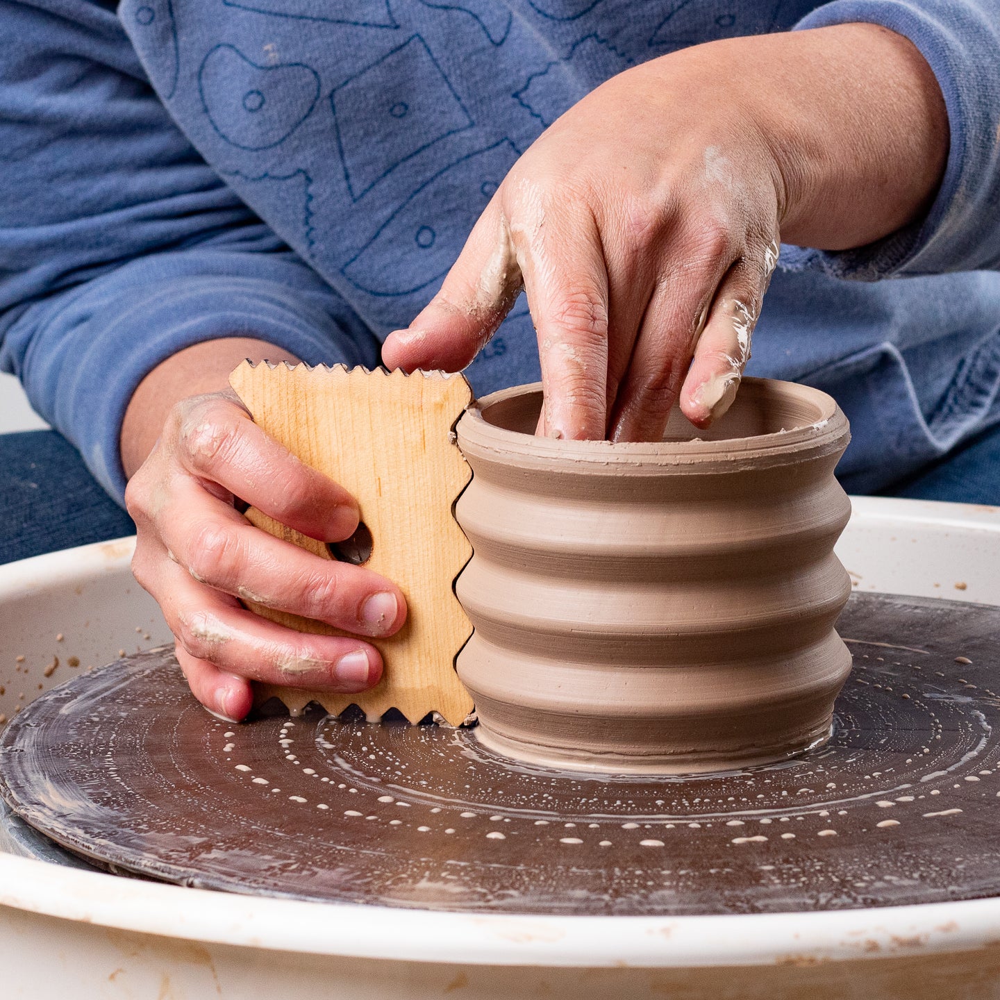 ceramicist uses Garrity Tools Texture 7 wooden pottery tool on clay vessel