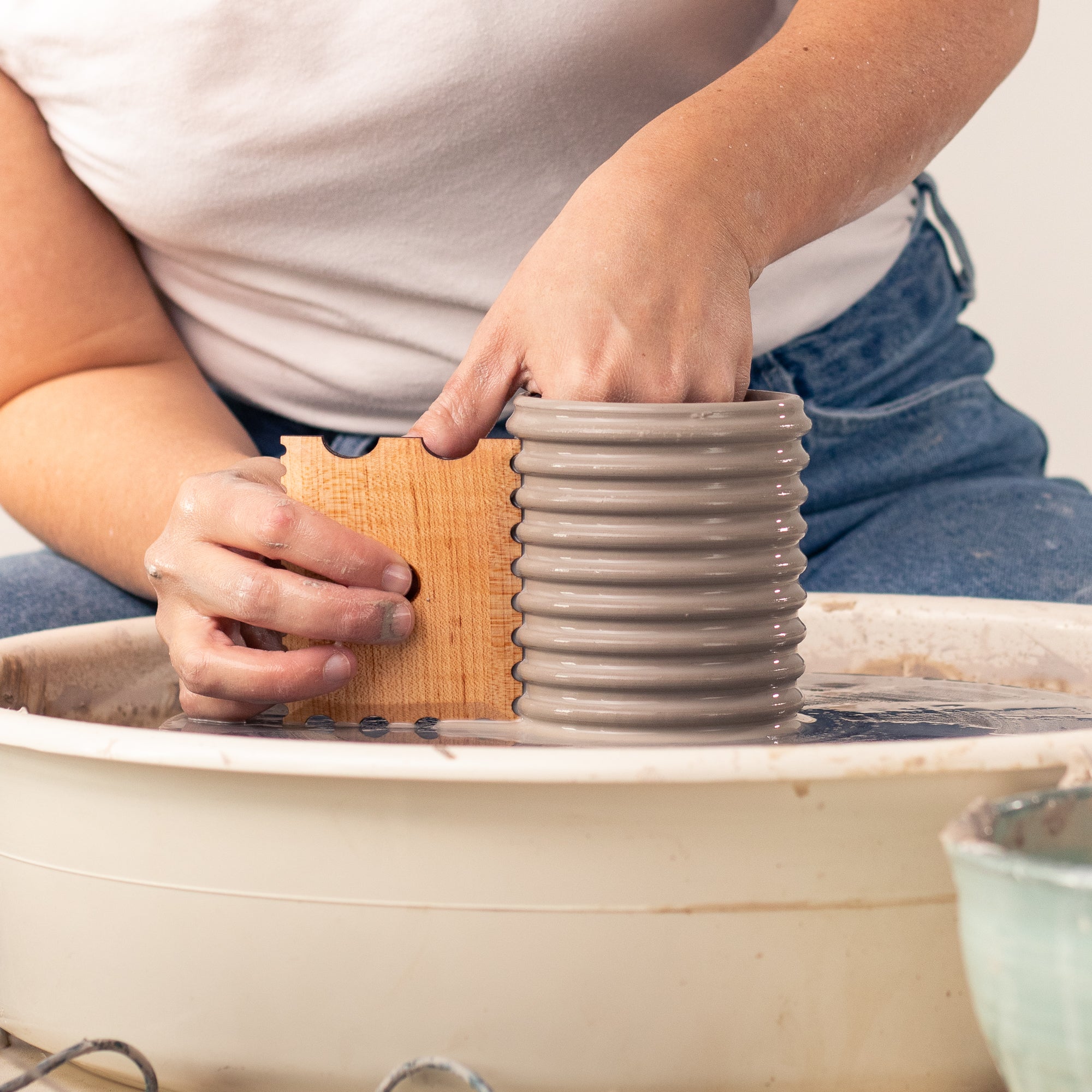 ceramicist uses Garrity Tools Texture 9 wooden pottery tool on clay cylinder