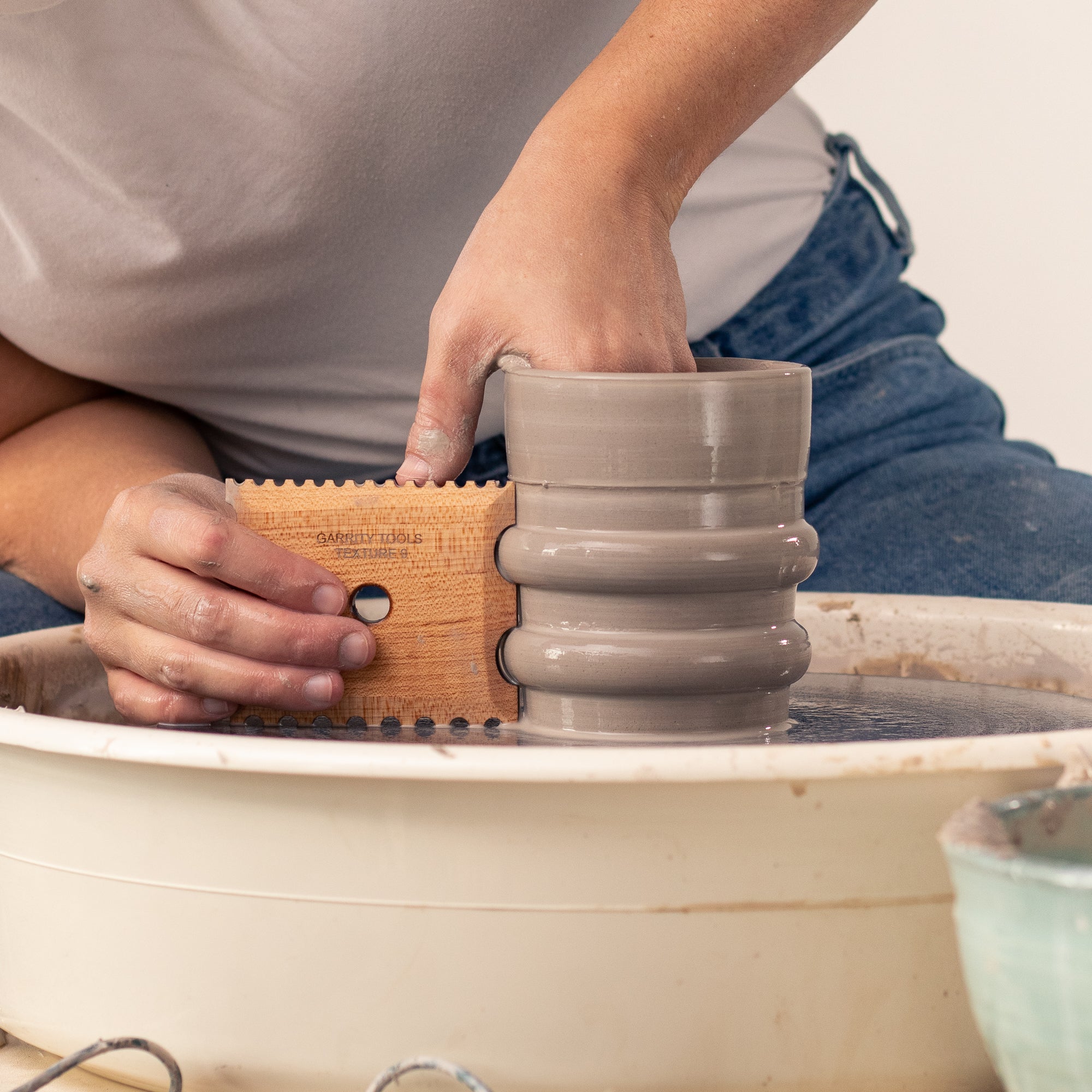 ceramicist uses Garrity Tools Texture 9 wooden pottery tool on pottery wheel