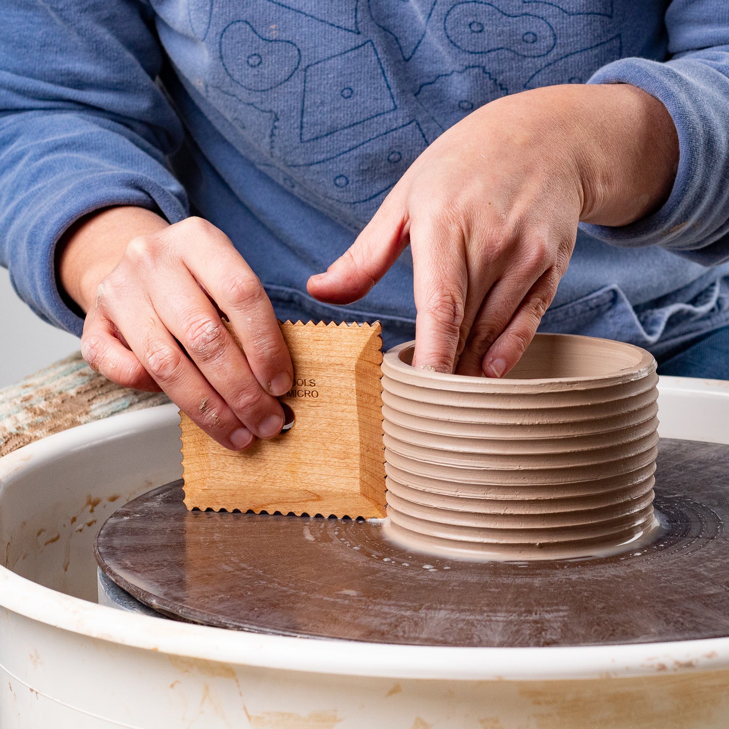 ceramicist uses Garrity Tools Texture Micro wooden pottery tool on clay cylinder