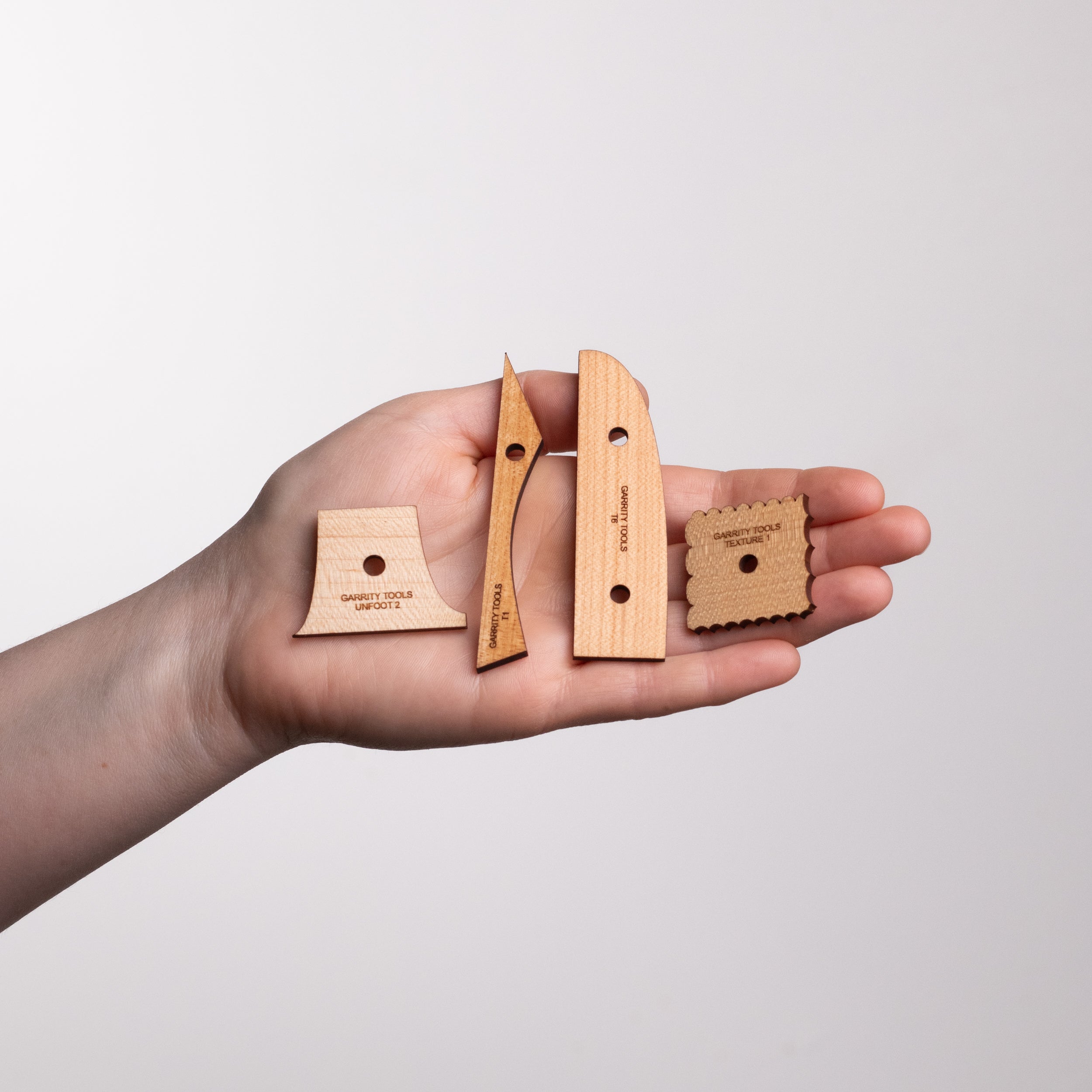 person holds tiny wooden pottery tools in the palm of their hand