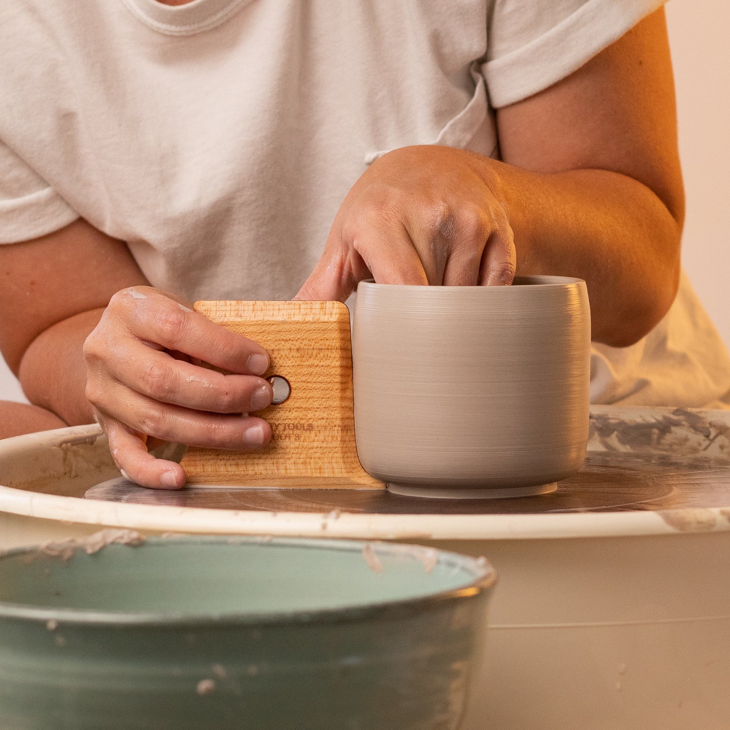 ceramicist uses Garrity Tools Unfoot 3 wooden pottery tool on clay mug